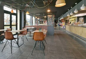 Un café moderno con barra, mesas y sillas, e iluminación colgante.