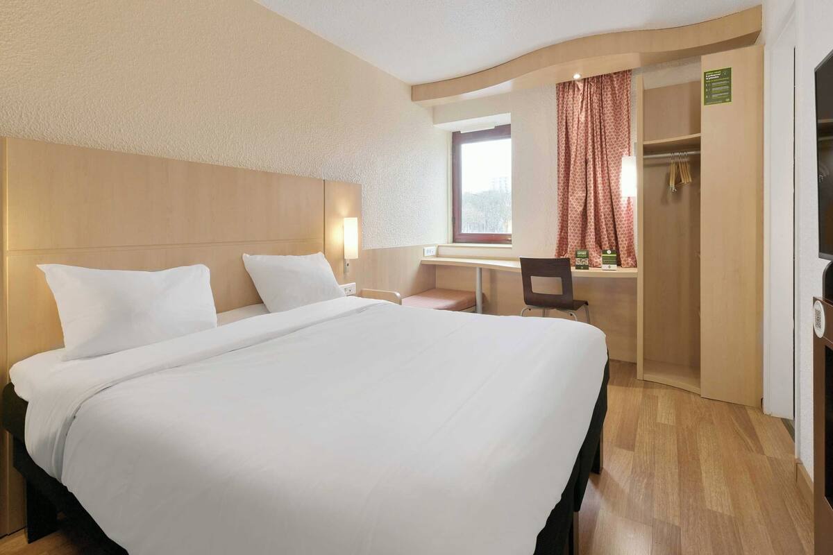 A hotel room with a large bed, a desk, and a chair.