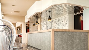 Un intérieur de restaurant moderne avec un îlot central, des chaises transparentes et des luminaires suspendus.