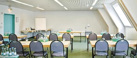 A conference room with tables and chairs, a whiteboard, and a green carpet.