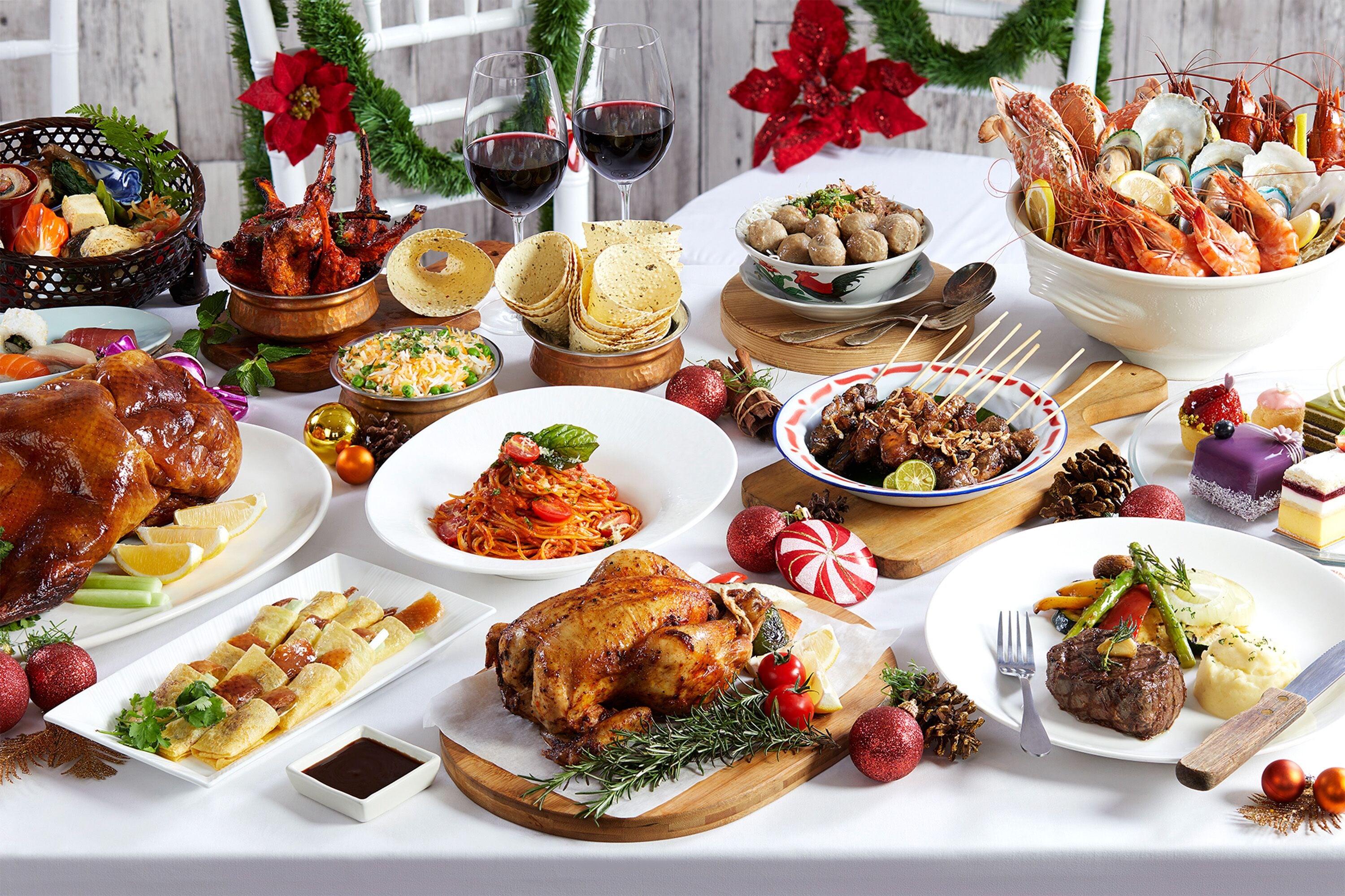 Une table festive, dressée avec divers plats, notamment du poulet rôti, des fruits de mer et du pain.