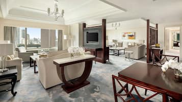 Amplia habitación de hotel con una zona de estar amplia, una mesa de comedor y un televisor.