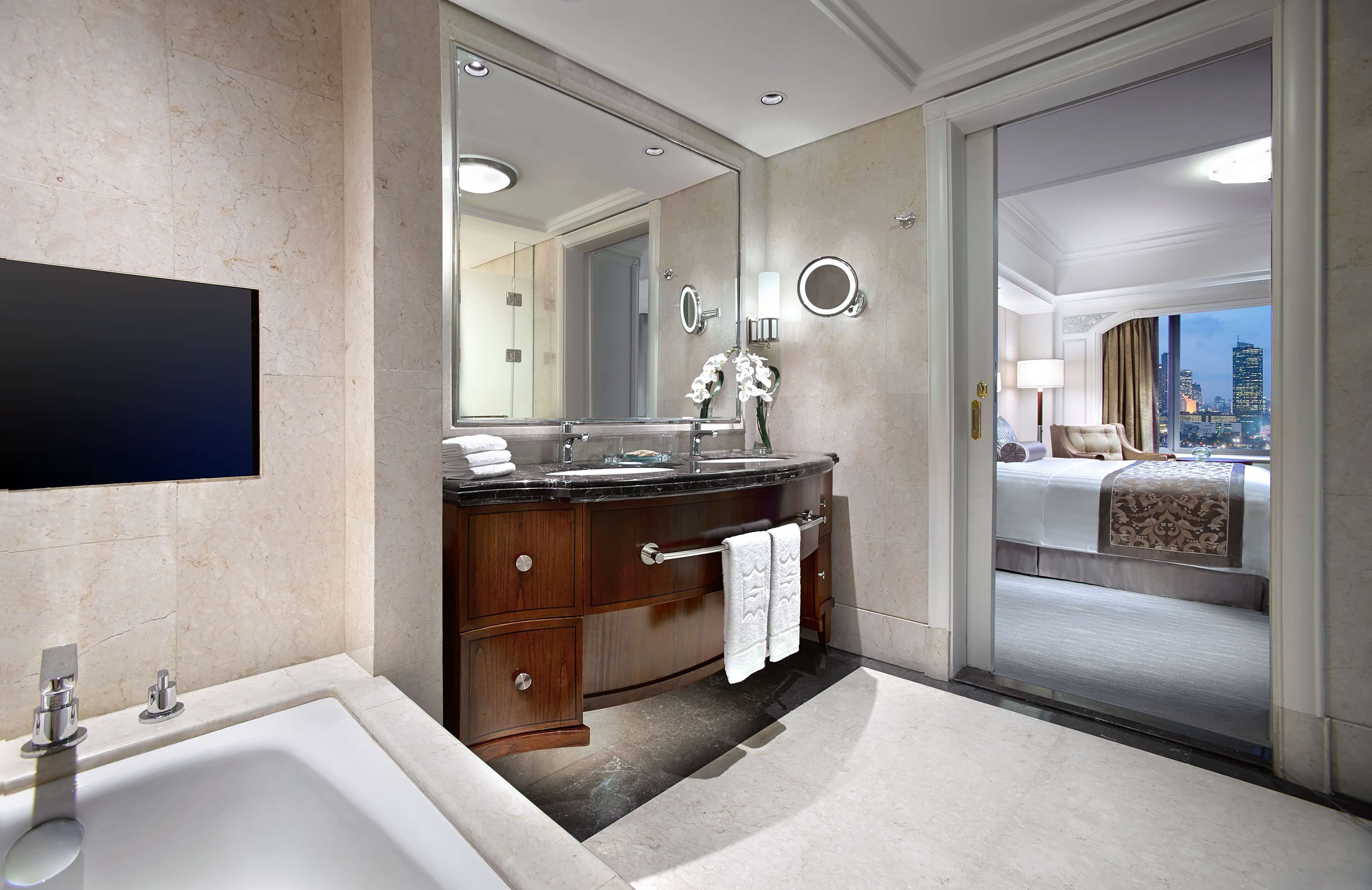 Un baño moderno con un espejo grande, una bañera y un tocador con un perchero.