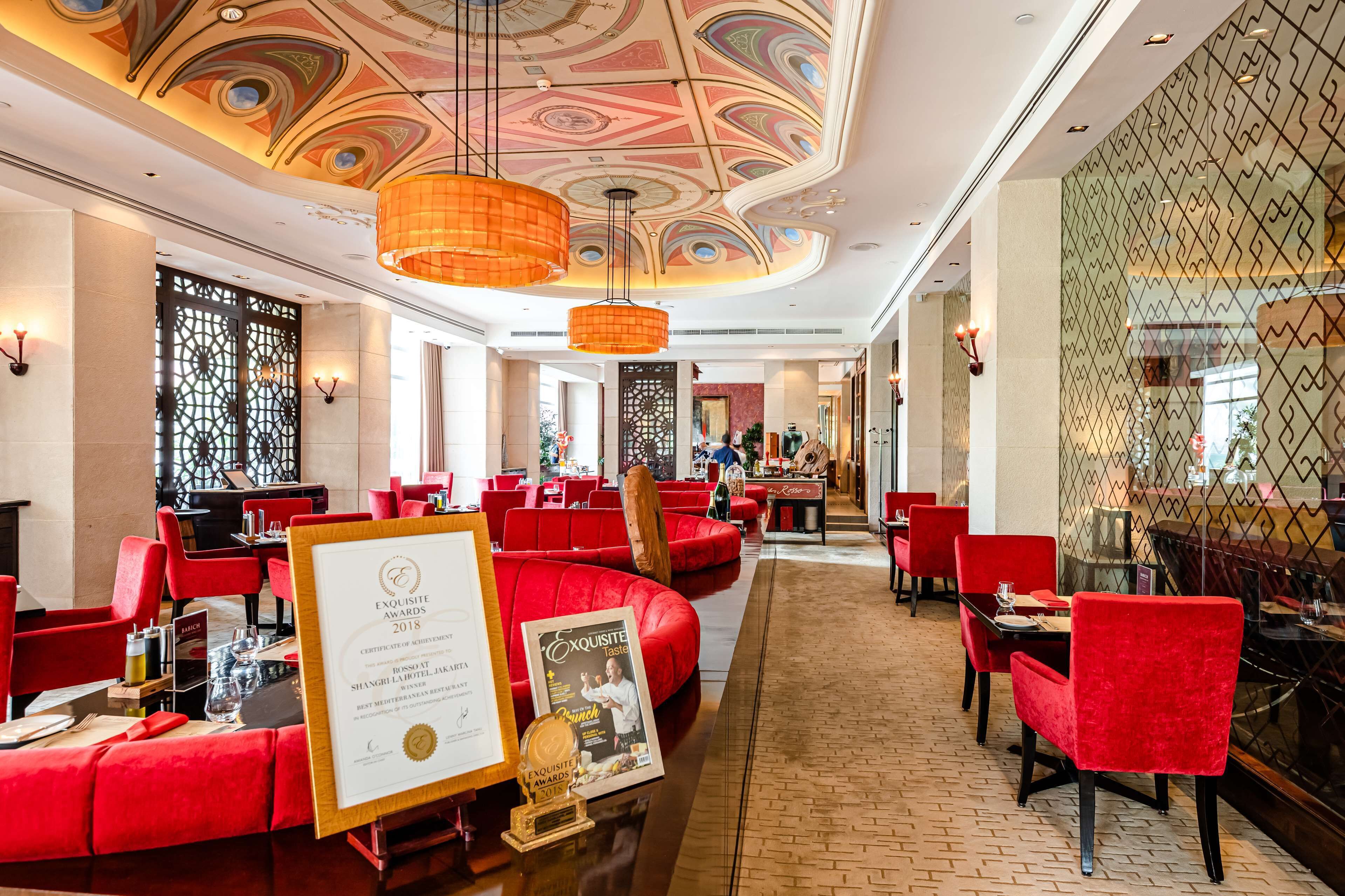 A restaurant with red upholstered seating, a patterned ceiling, and a certificate on the table.