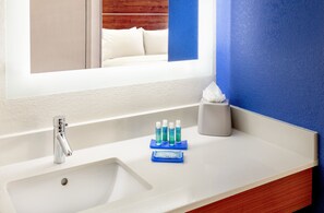 A bathroom with a white sink, a mirror, and a blue wall.