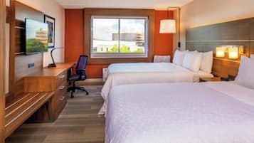 Camera d'albergo con due letti, una scrivania, una sedia, una televisione e una finestra vista edifici.