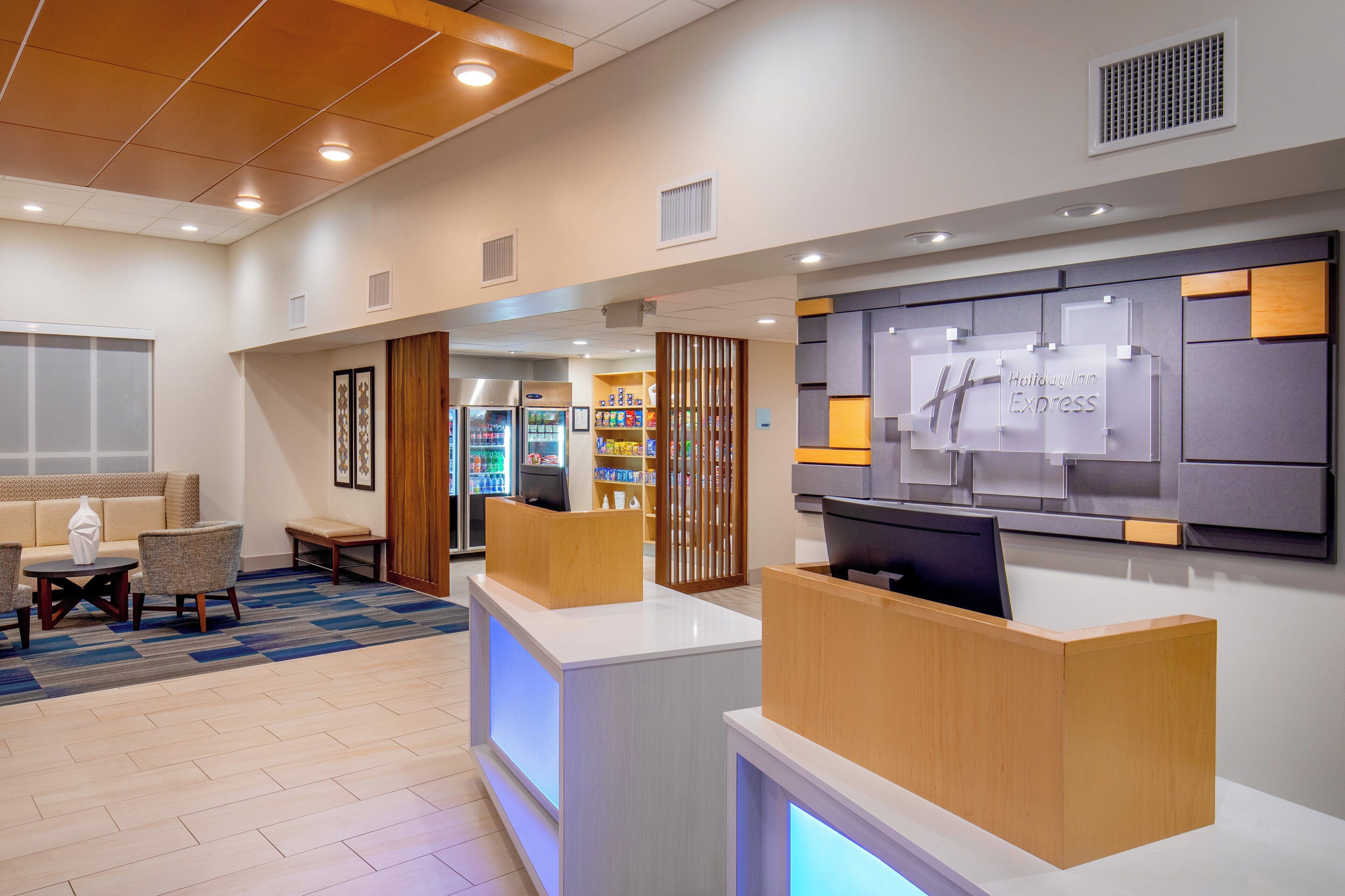 Ein Hotel-Rezeptionsbereich mit Empfangstresen, Sitzgelegenheit und Wanddisplay.