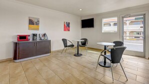 Una habitación con kitchenette, dos sillas, una mesa pequeña, un televisor montado en la pared y una ventana que ofrece vistas al exterior.