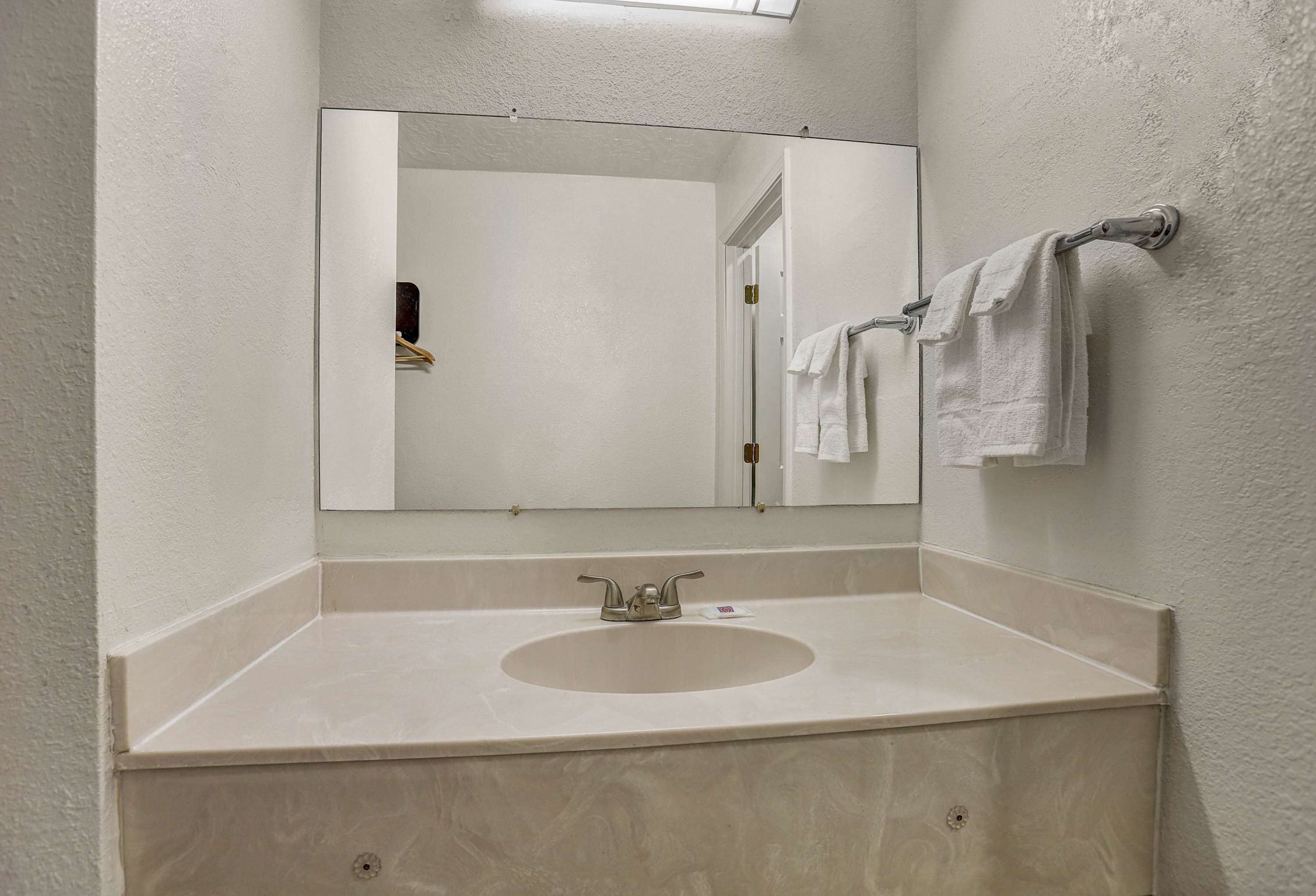 A bathroom with a sink, mirror, and towel rack.