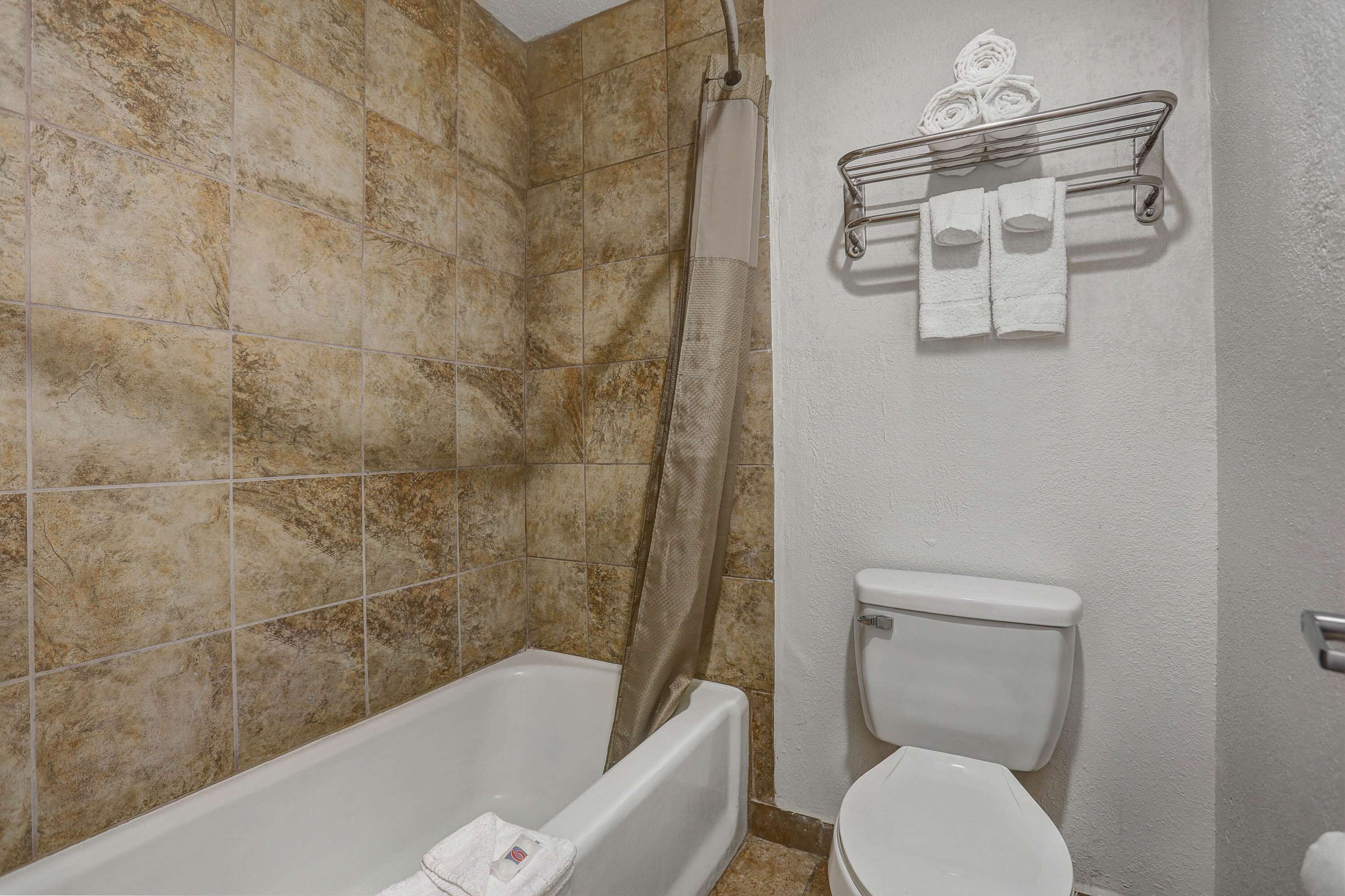 A bathroom with a bathtub, toilet, and shower curtain.