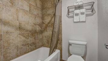 A bathroom with a bathtub, toilet, and shower curtain.
