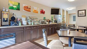 A breakfast area with waffle and hot food stations, seating, and a flat-screen TV. - Quality Inn Hays I-70 (Hays)
