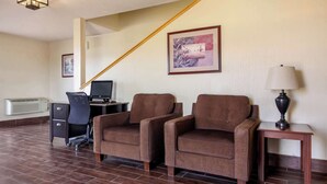 A hotel room with a desk, two armchairs, a lamp, a framed picture, and a staircase. - Quality Inn Hays I-70 (Hays)