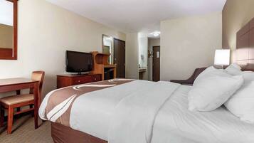 Een hotelkamer met een groot bed, een bureau met stoel, een televisie en een lamp.