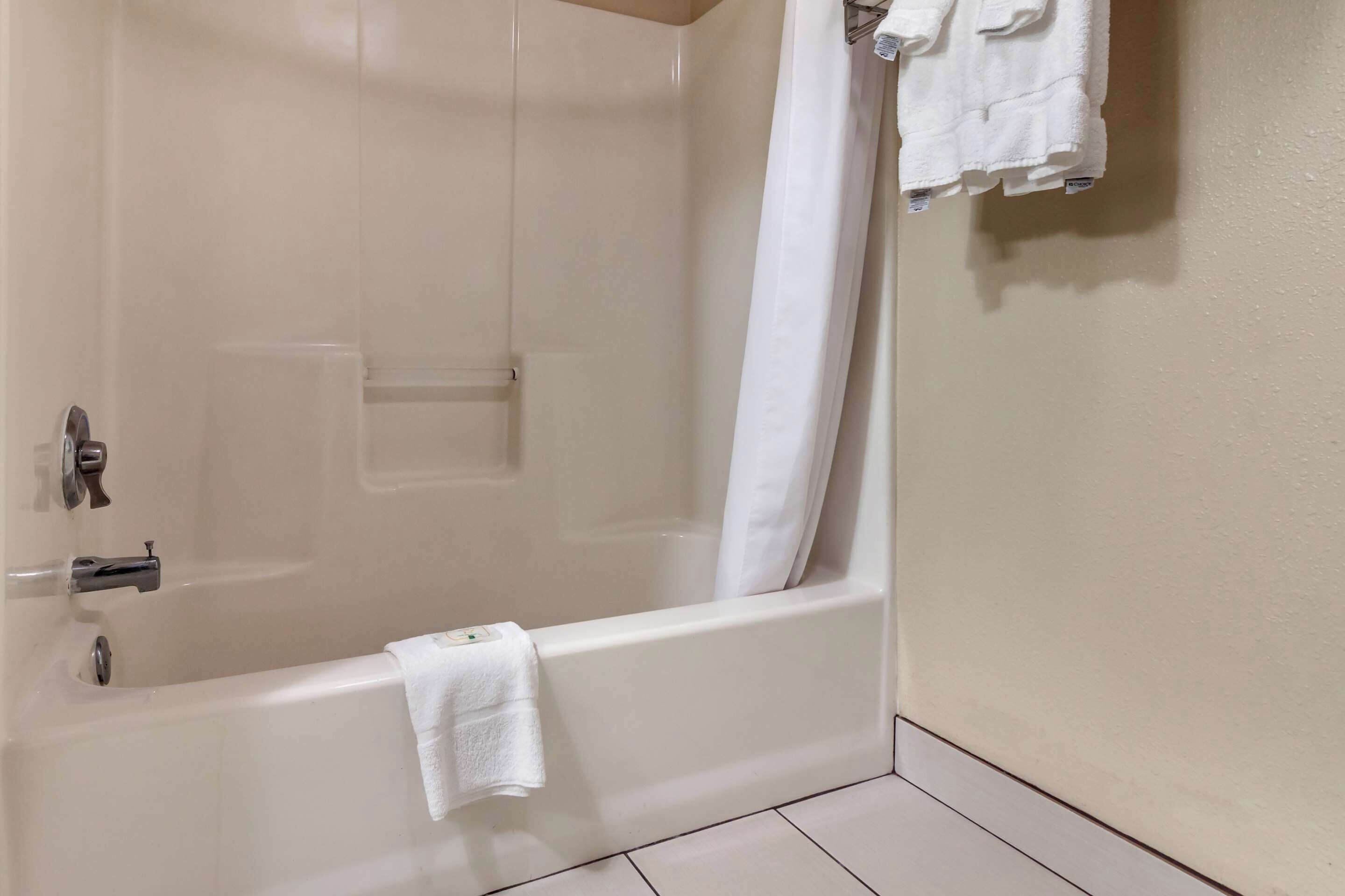 A bathroom with a bathtub, a shower curtain, and a towel hanging on the wall.