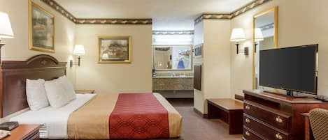 Habitación de hotel con cama, cómoda, televisor y baño visible a través de una puerta abierta.