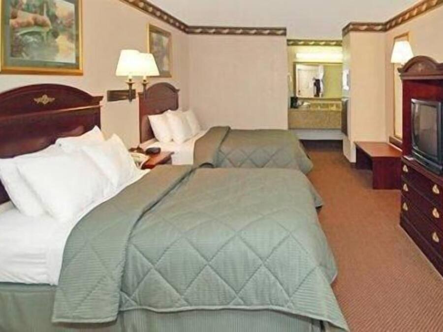 Una habitación de hotel con dos camas, un televisor, un espejo y un aparador.