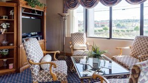 A living room with a large window, a television, and a bookshelf. - Econo Lodge Grenada (Grenada)