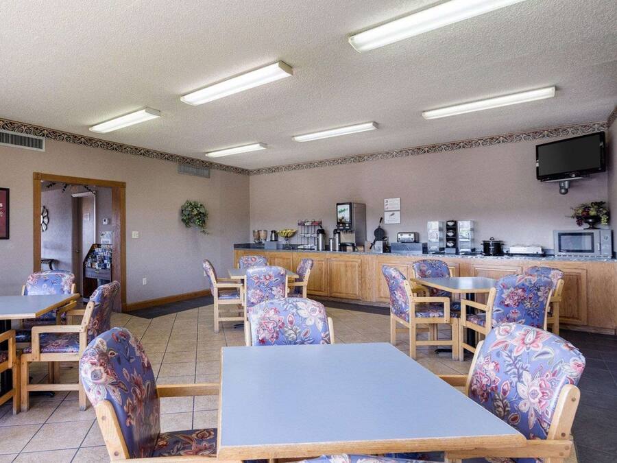 A restaurant with a counter, chairs, tables, and a television mounted on the wall.