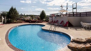 A swimming pool with a tiled edge, surrounded by lounge chairs and a small deck area. - Econo Lodge Grenada (Grenada)