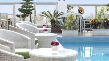 Zona de piscina con mobiliario de mimbre y plantas en macetas.