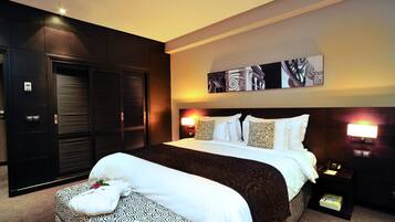 Una habitación de hotel con una cama grande, un armario, una mesita de noche con lámpara y una obra de arte colgada en la pared.