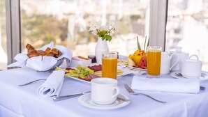 A breakfast table with croissants, fruit, and a glass of orange juice. - Mövenpick Hotel Casablanca (Casablanca)