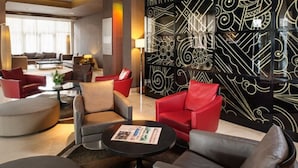A modern lounge area with sofas and armchairs, a coffee table, and a decorative wall with geometric patterns. - Mövenpick Hotel Casablanca (Casablanca)