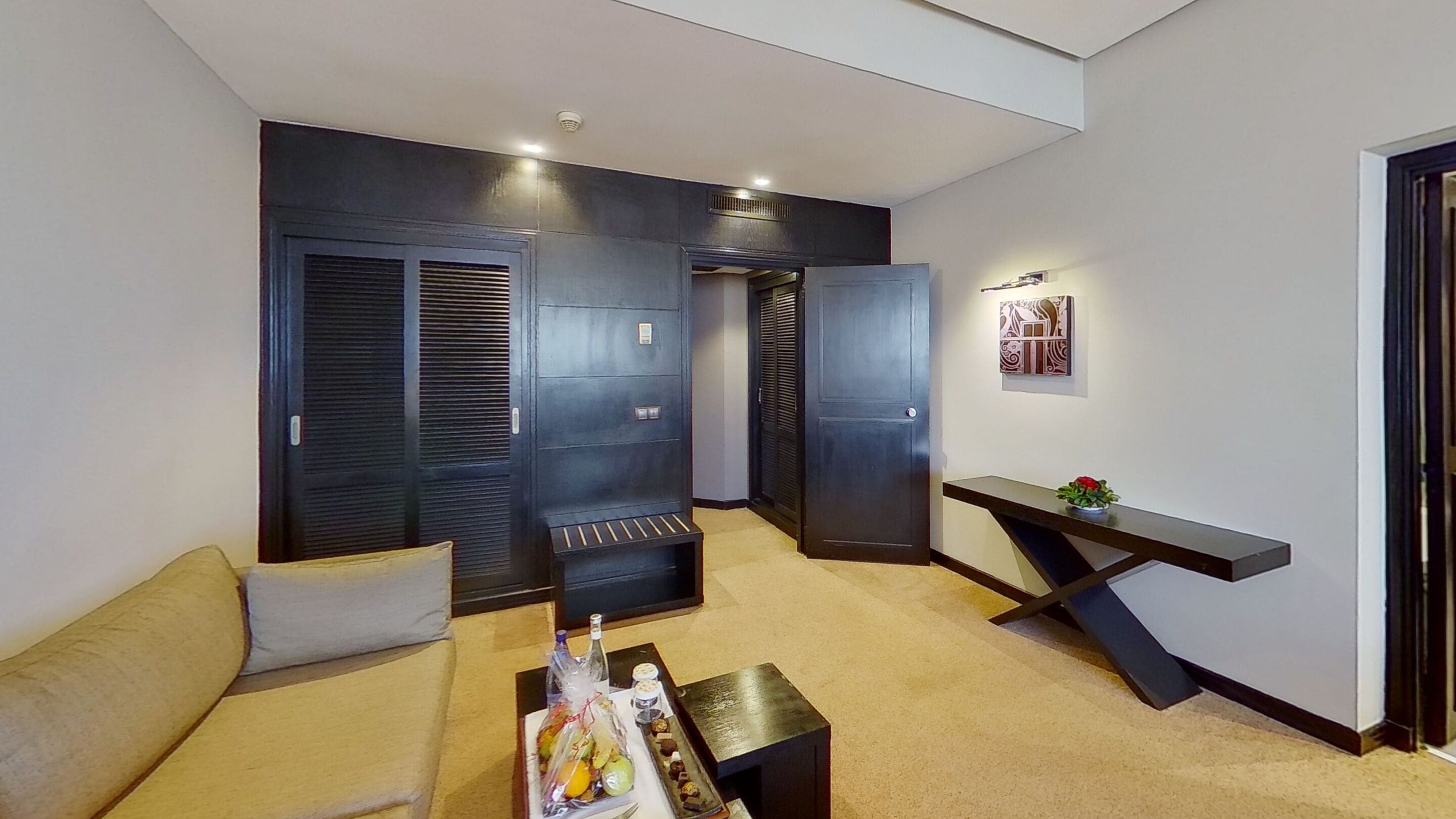 A modern living room with a sofa, a coffee table with snacks, and a decorative wall piece.