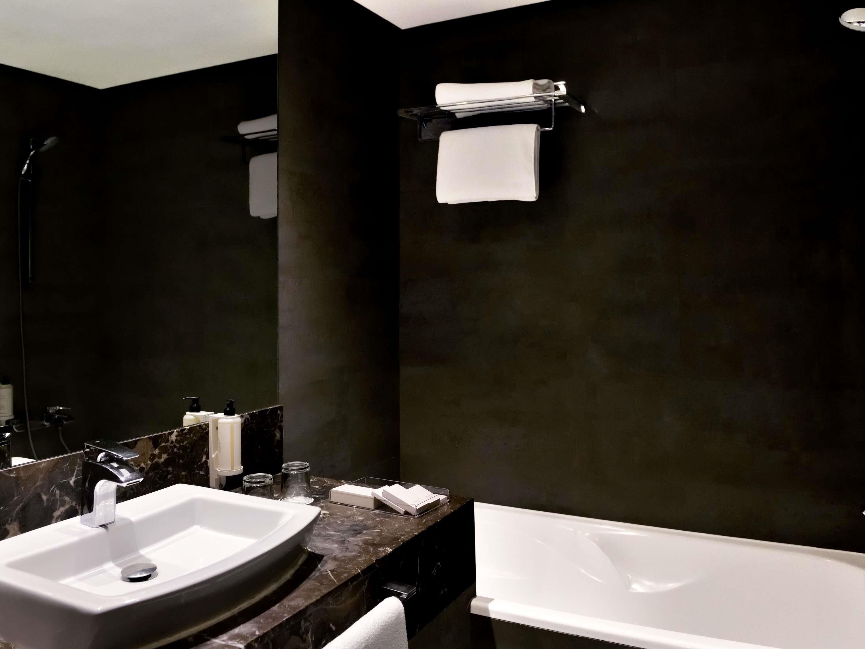 Un baño moderno con un lavamanos grande, una bañera y un espejo.