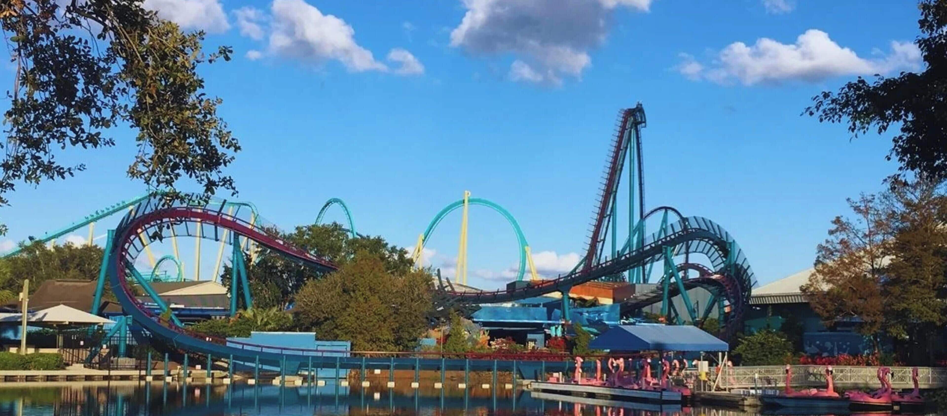 A theme park with roller coasters and a body of water reflecting the rides.