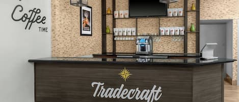 Een koffiebar interieur met een donkere toonbank, koffiemachines en planken met koffiezakken.