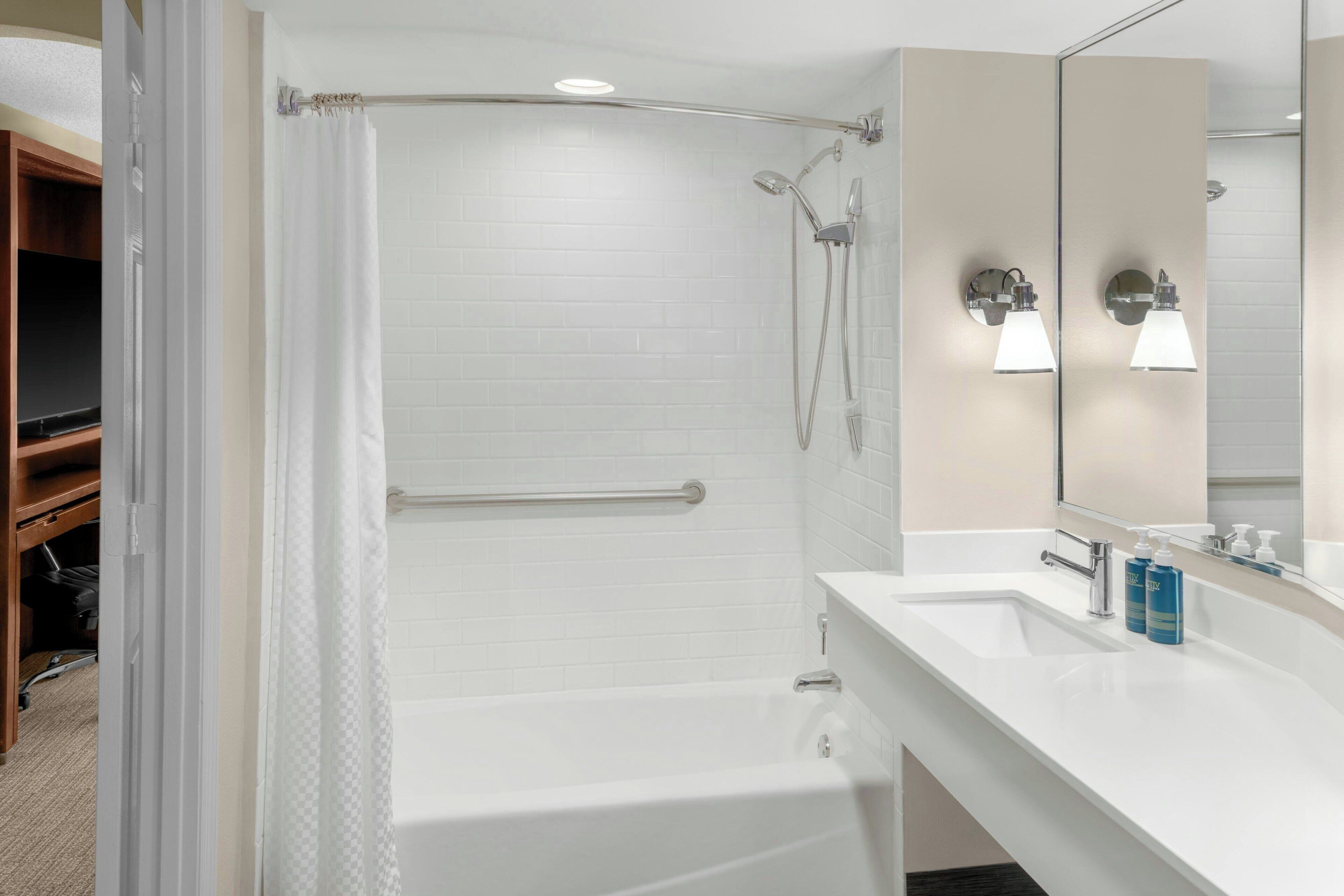 Une salle de bain moderne équipée d’une baignoire, d’une douche et d’un meuble-lavabo avec un miroir.