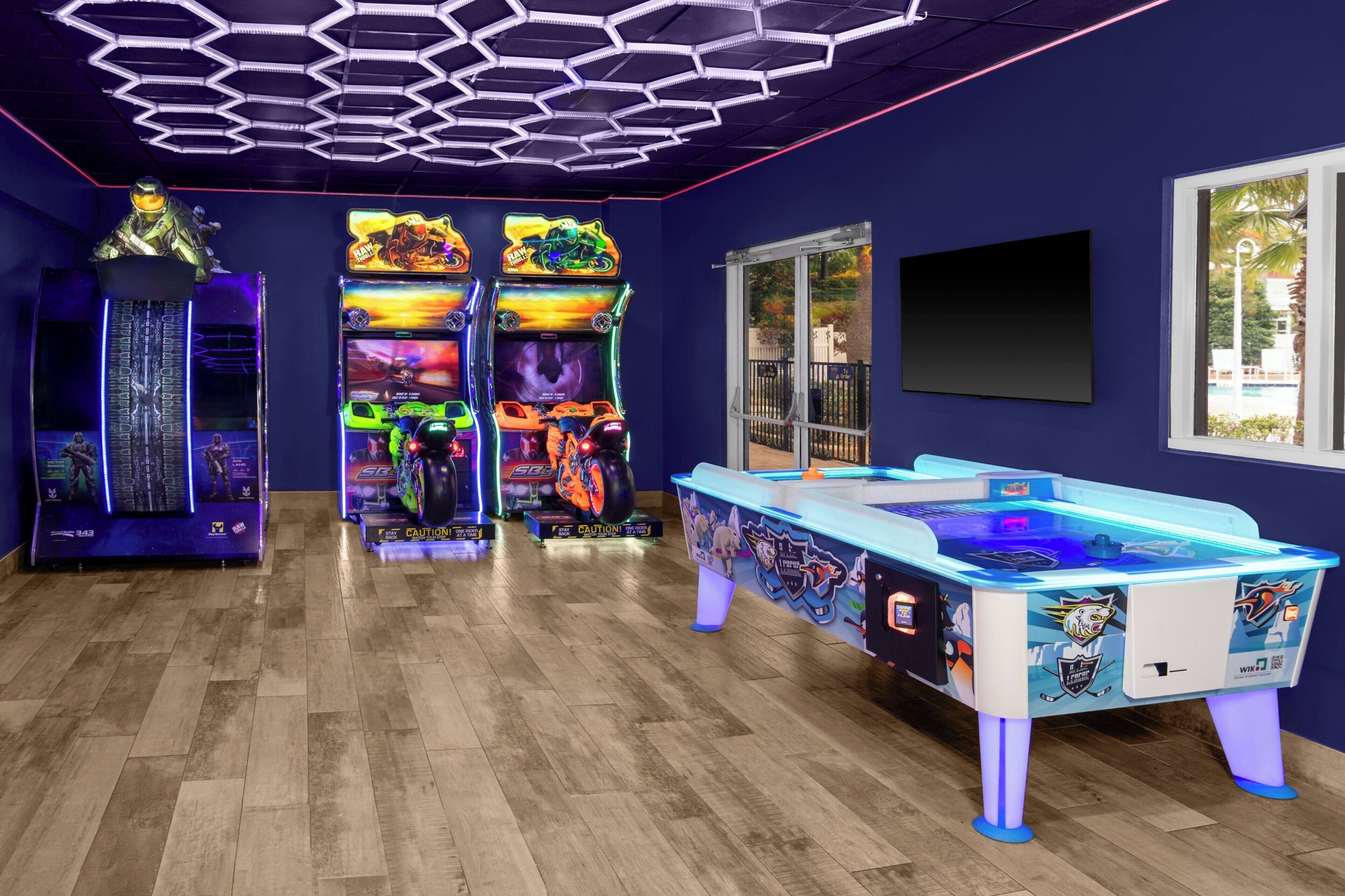 A room with arcade games, a pool table, and a large window.