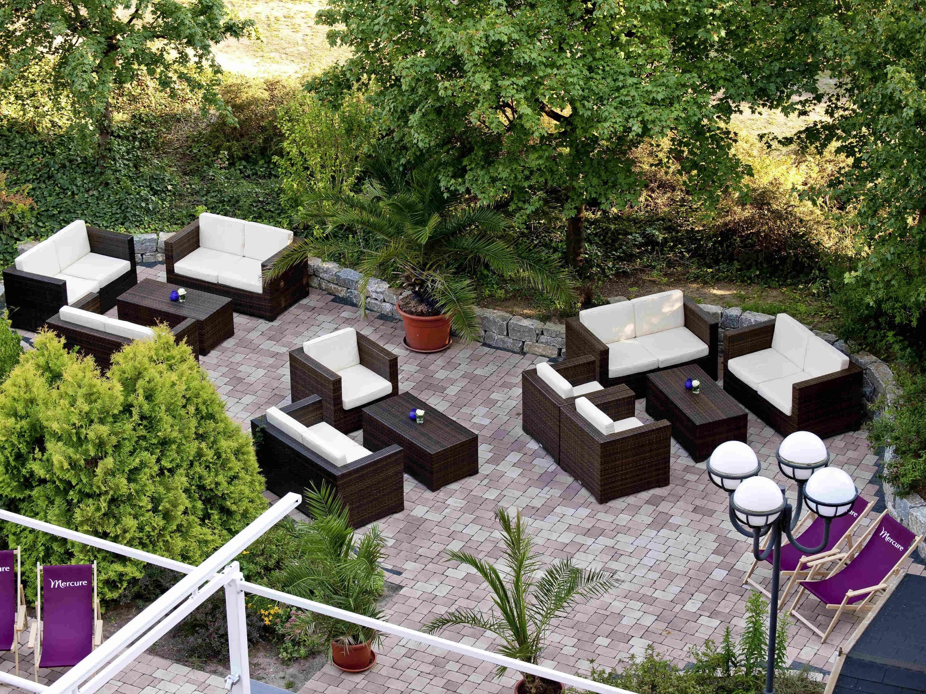 An outdoor seating area with wicker furniture and a paved patio.
