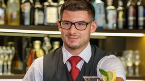 A bar setting with a bartender holding a cocktail.