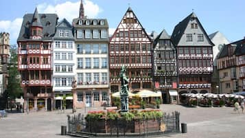 A historic square with traditional half-timbered buildings, a central statue, and outdoor seating areas.