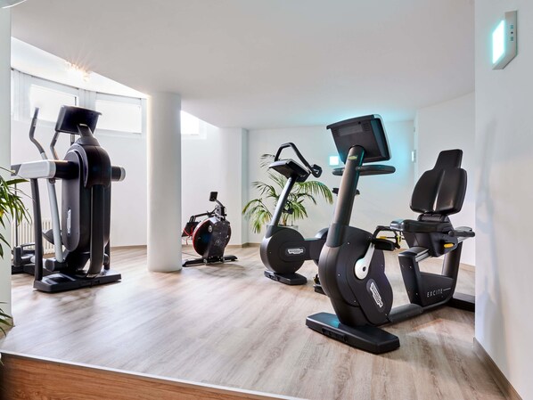 A modern gym with stationary bikes, ellipticals, and a rowing machine.