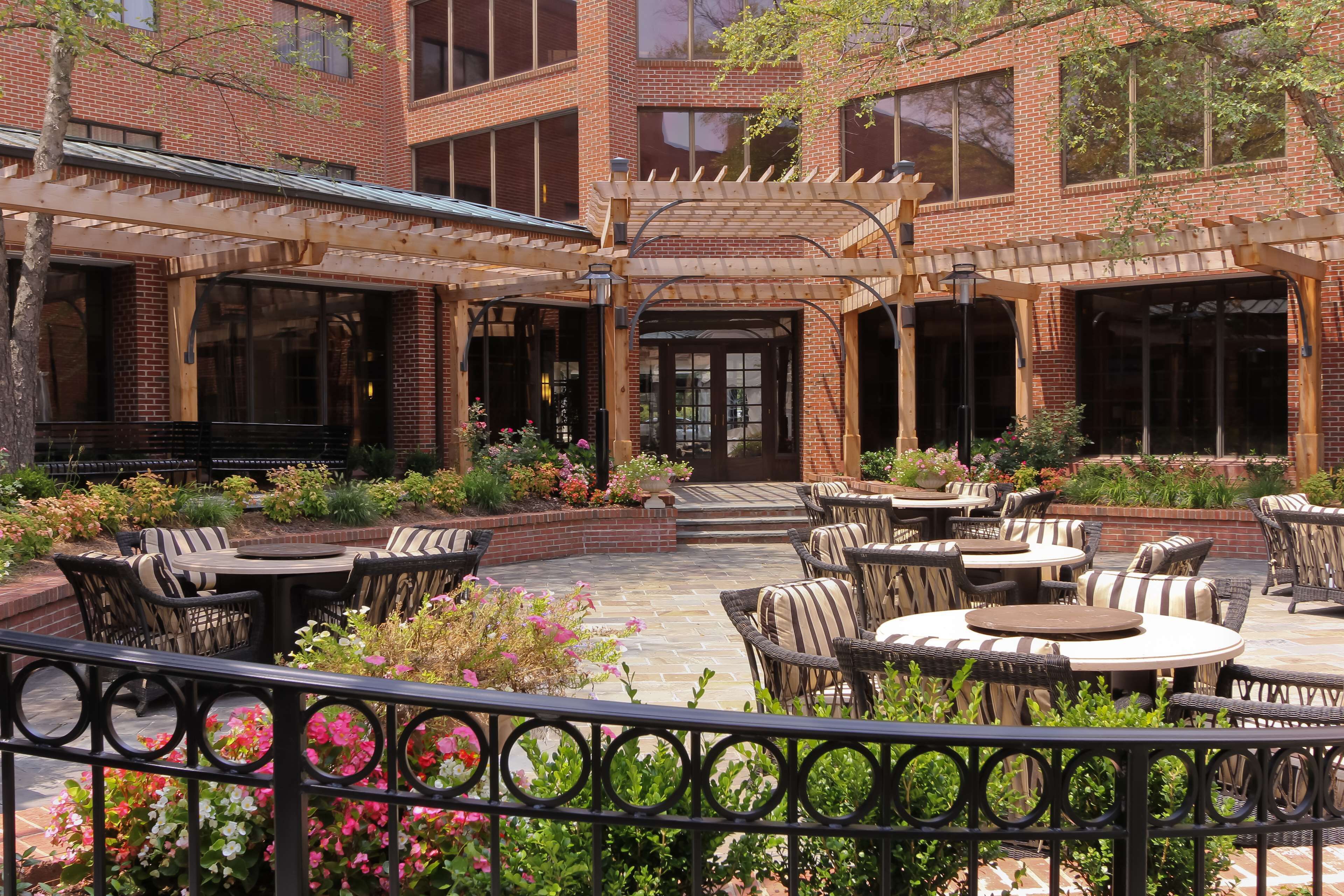 A courtyard with outdoor seating, brick buildings, and a pergola.