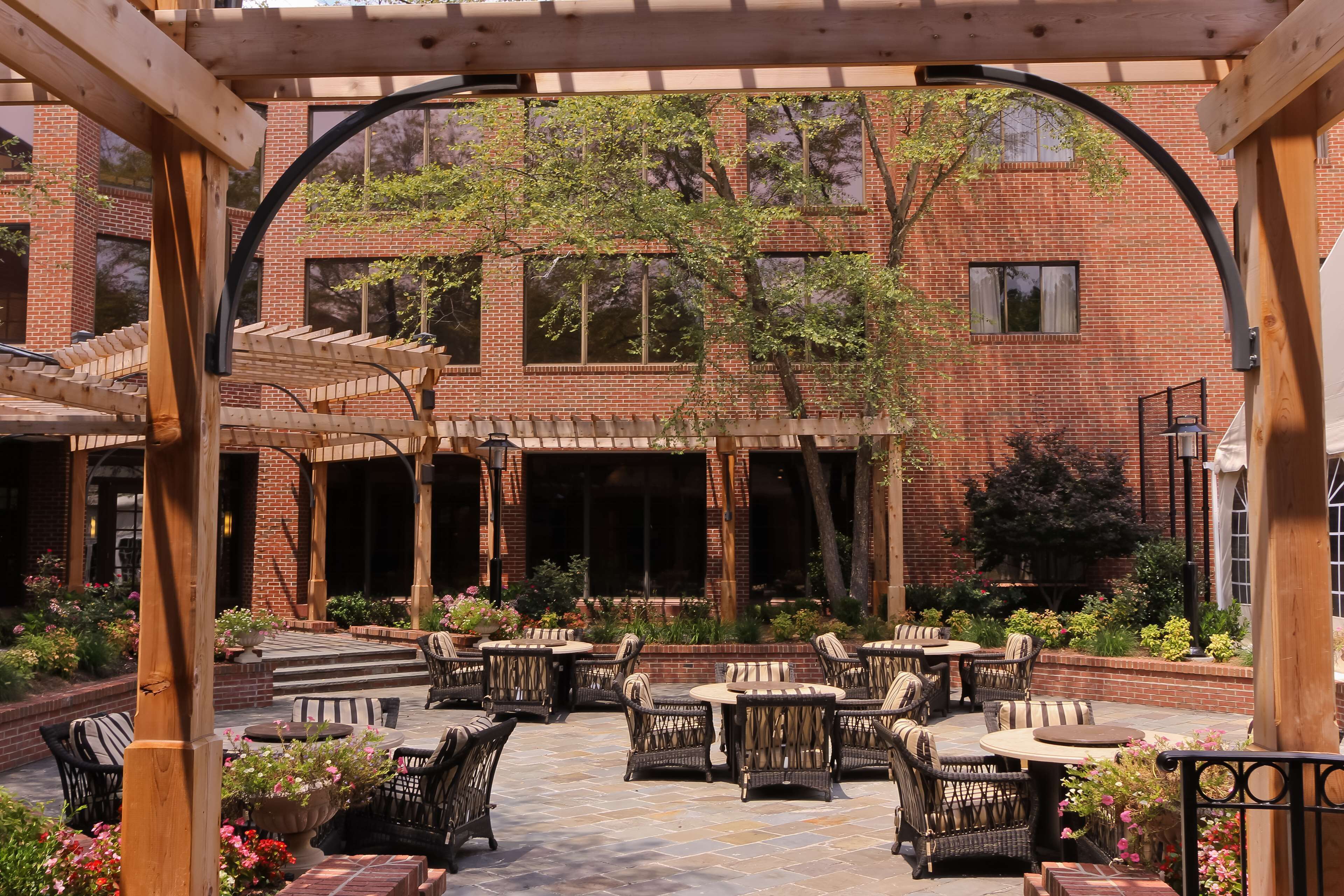 A brick building with a covered patio area featuring outdoor seating with wicker furniture and potted plants.