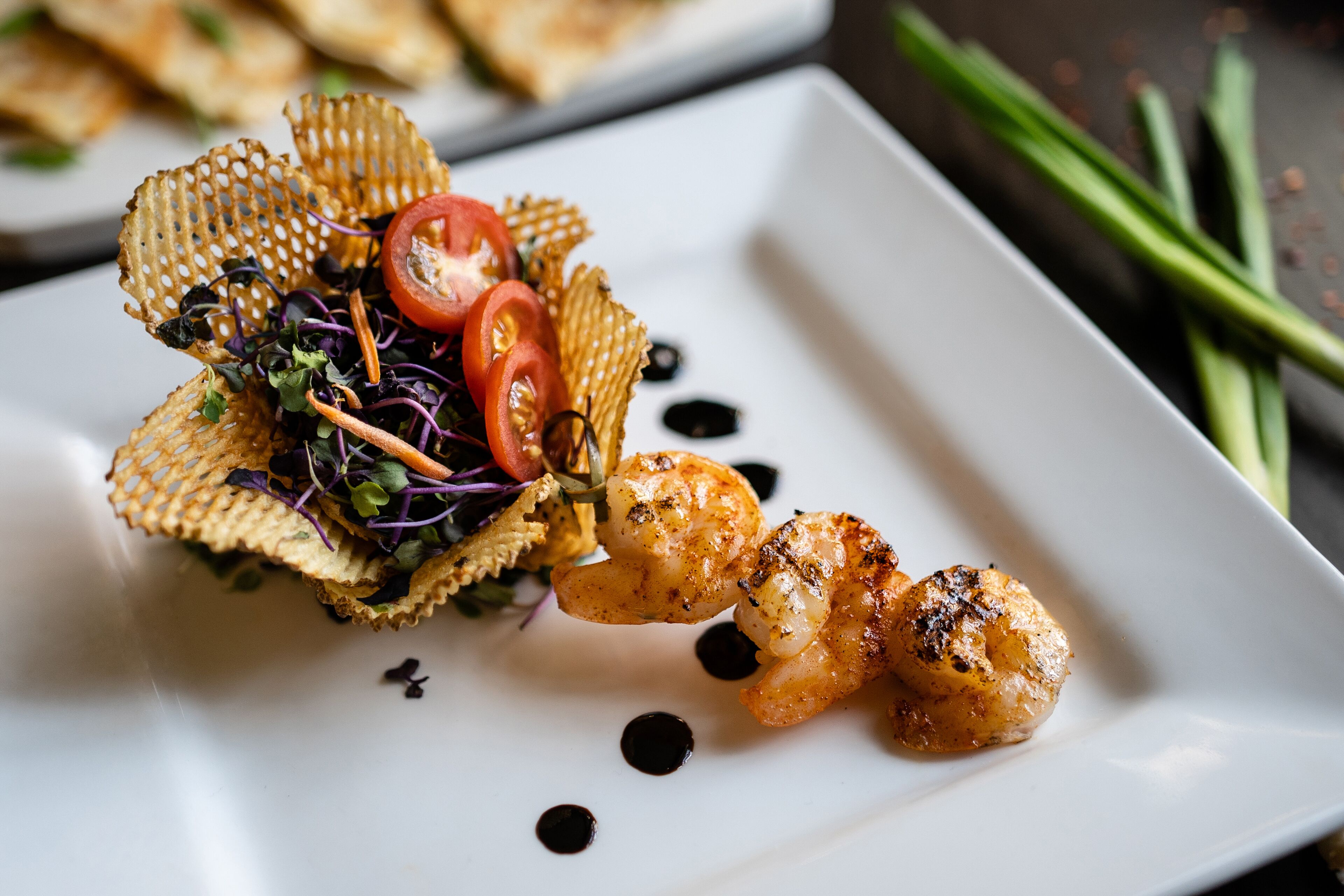 Une assiette comprenant des crevettes grillées, une salade et un élément décoratif.