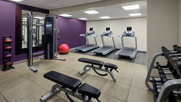 Une salle de sport équipée de tapis de course, d’appareils de musculation et d’un miroir.