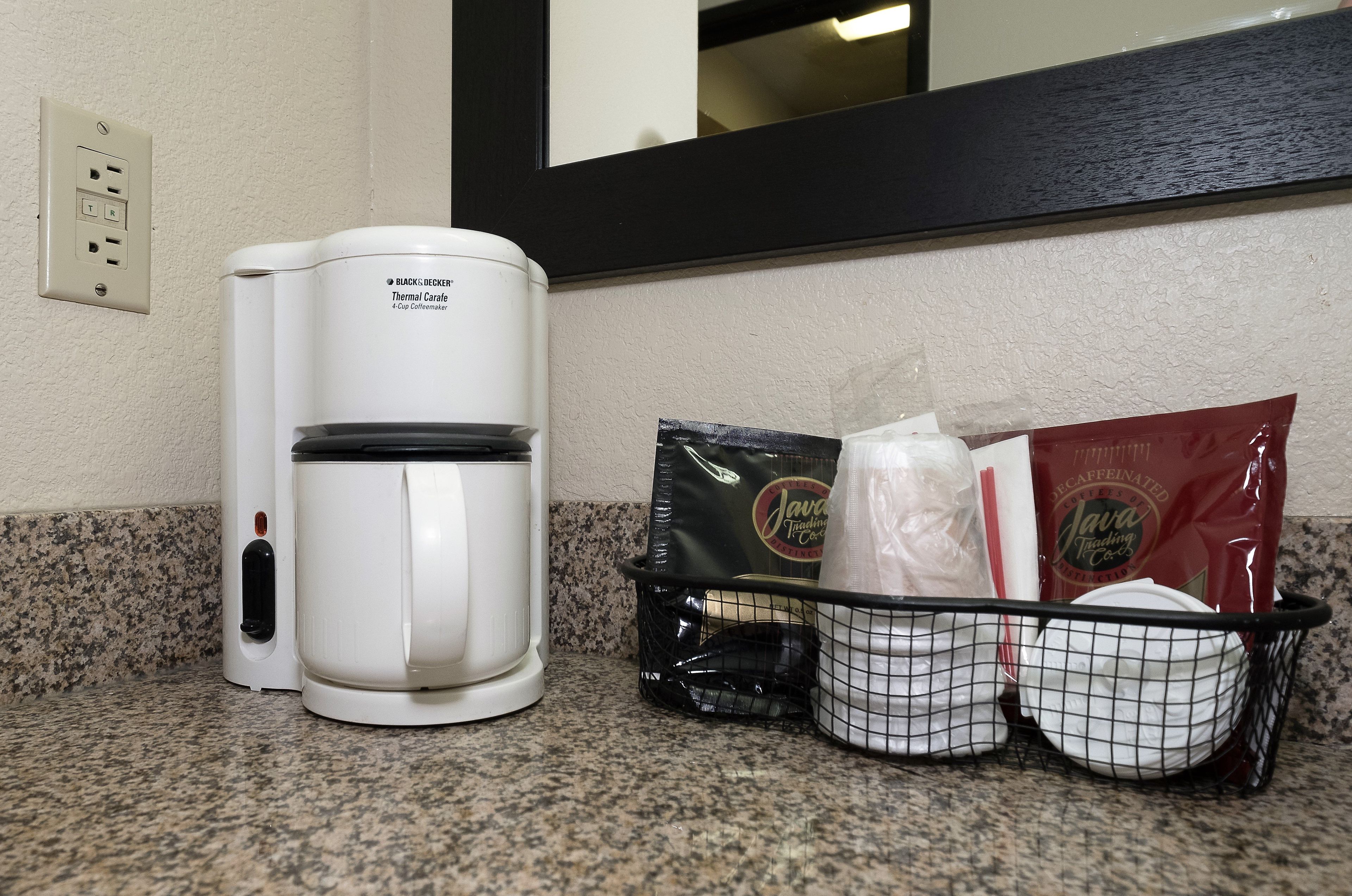 A coffee maker, a basket with coffee pods, and a bag of coffee on a countertop.