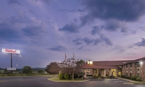 A Red Roof Inn & Suites with a brick building, a parking lot, and a cloudy sky. - Red Roof Inn & Suites Hermitage (Hermitage)