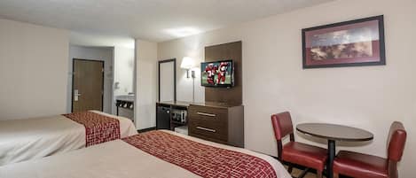 Habitación de hotel con dos camas, un escritorio con silla, televisor, espejo y un cuadro en la pared.