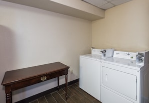 A laundry room with a wooden table and a white washer and dryer. - Red Roof Inn & Suites Hermitage (Hermitage)