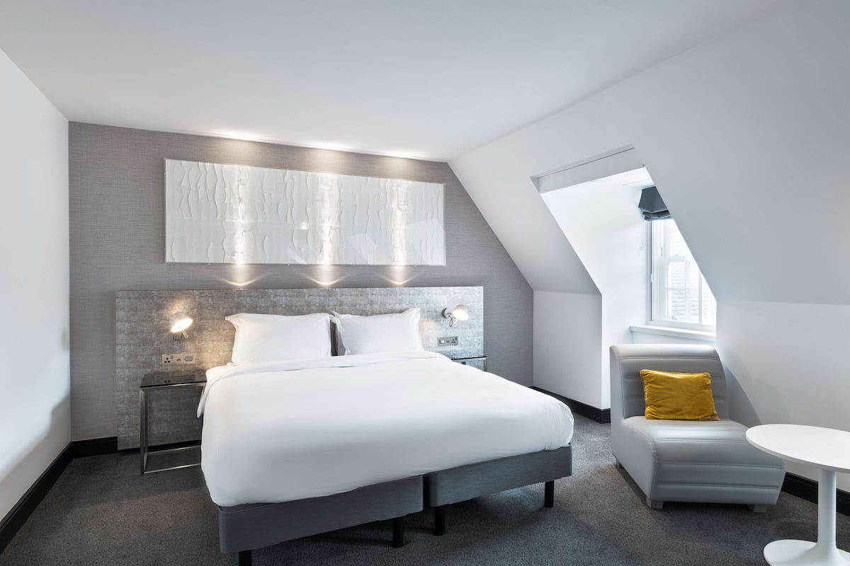 Une chambre d’hôtel moderne dotée d’un grand lit, d’un petit coin salon et offrant une vue sur la ville.