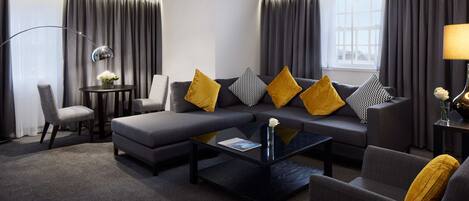 A modern living room with a grey sofa, yellow cushions, a black coffee table, and a grey armchair.