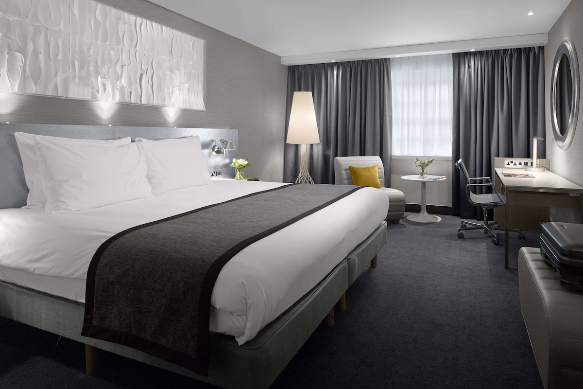 Une chambre d’hôtel moderne équipée d’un grand lit, d’un bureau, d’une chaise et d’une petite table.