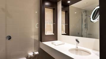 A modern bathroom with a large mirror, a sink, and a toilet.